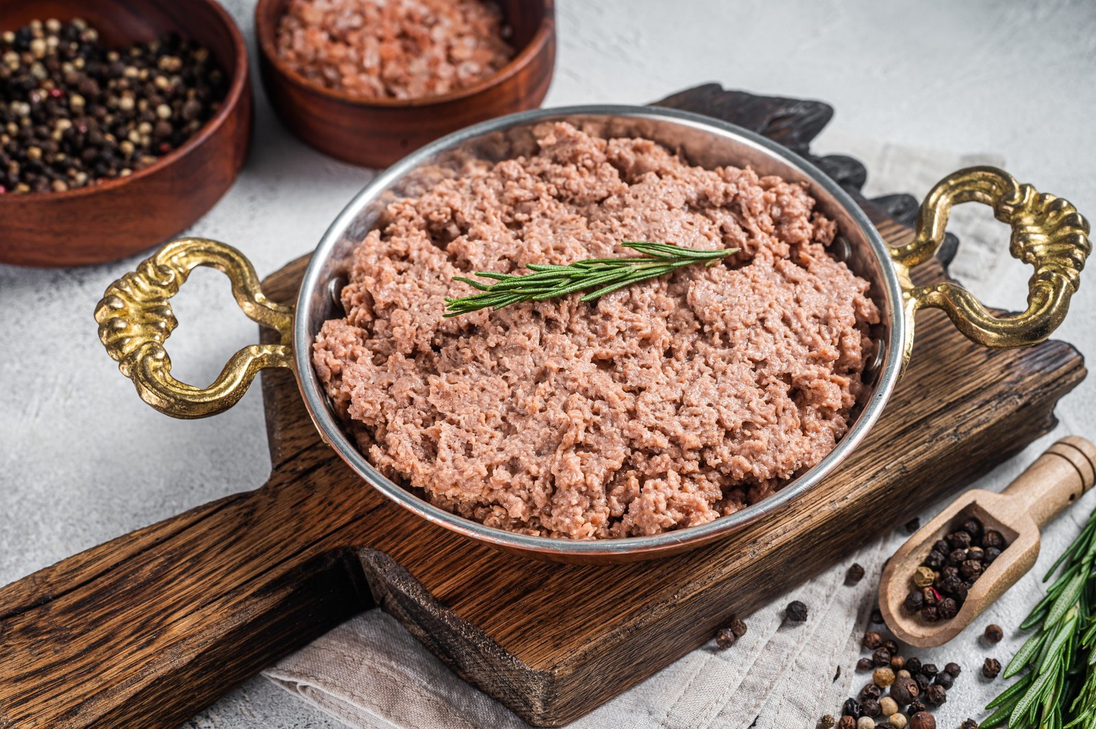 Uncooked vegan mince meat, raw plant based meat with thyme in skillet. White background. Top view