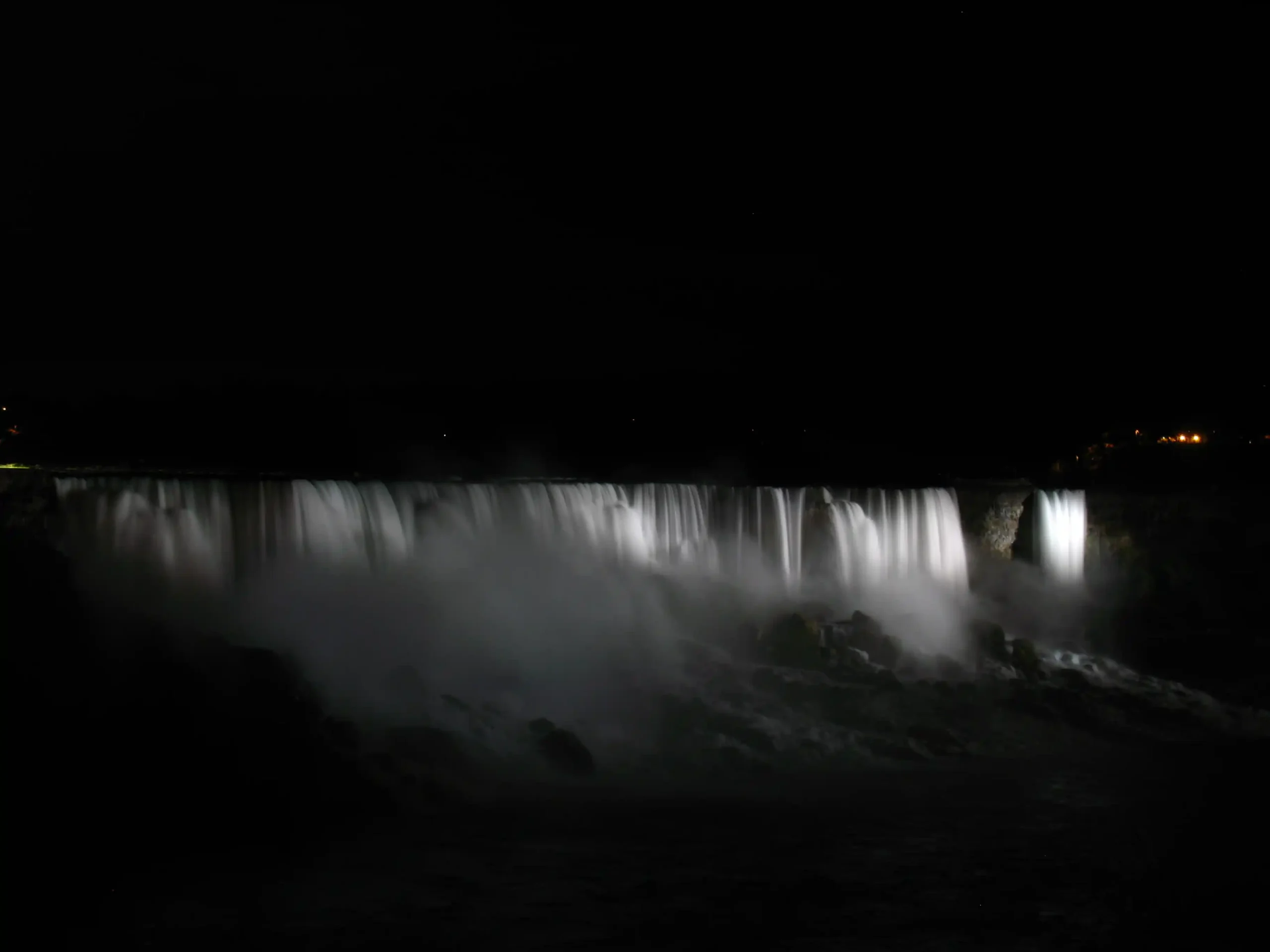 Night view of Niagara Falls with illuminated mist and city lights